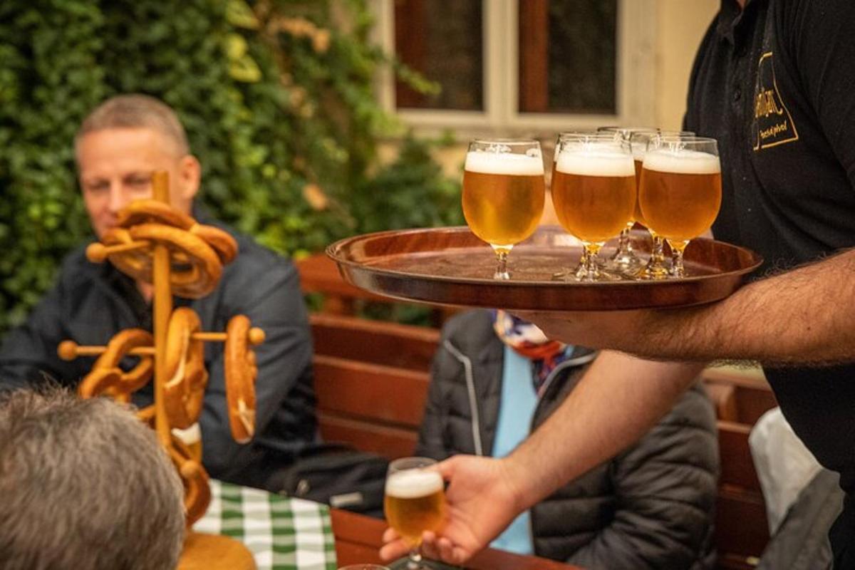 muž držící tác se čtyřmi sklenicemi piva