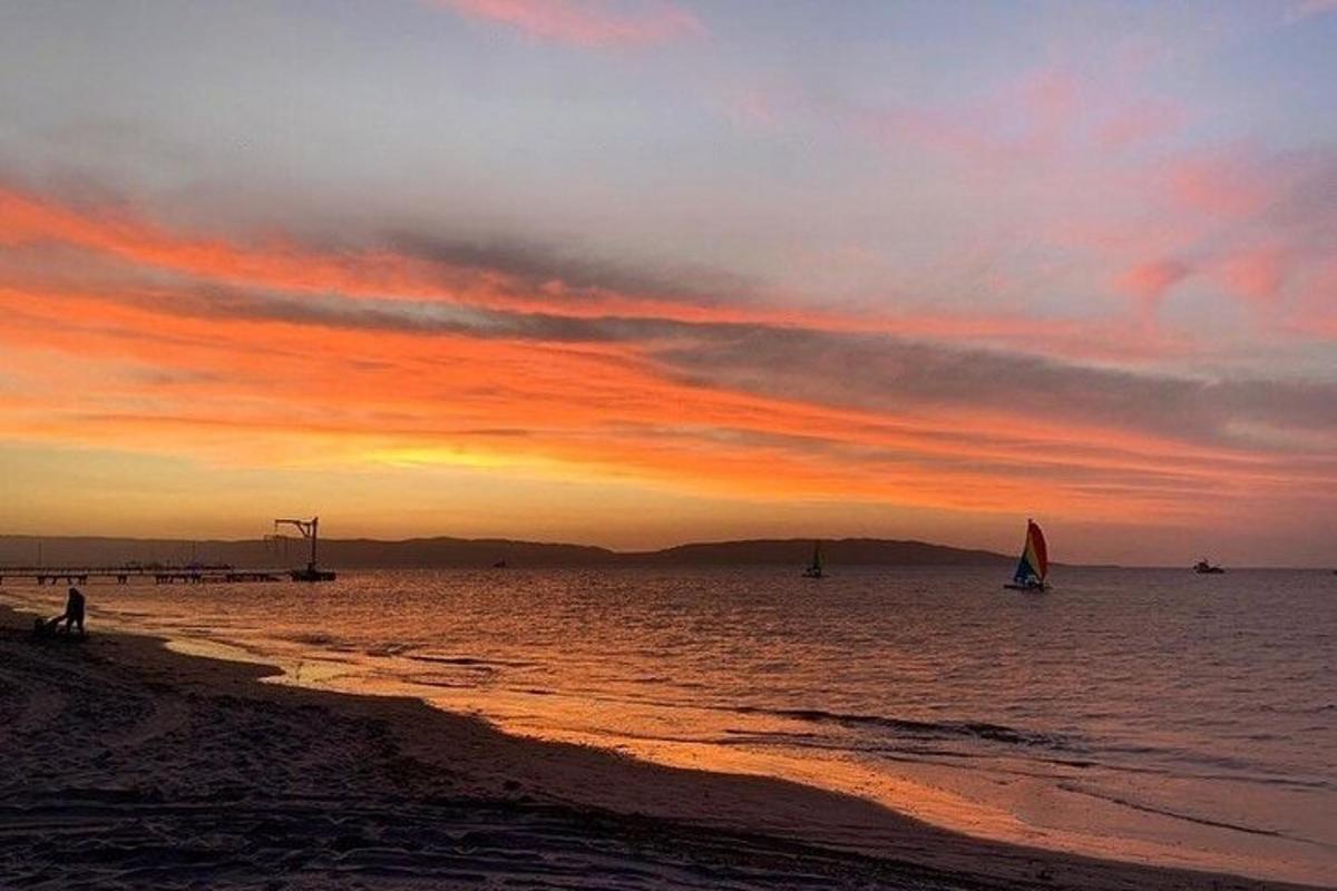 a sunset on the beach with boats in the water