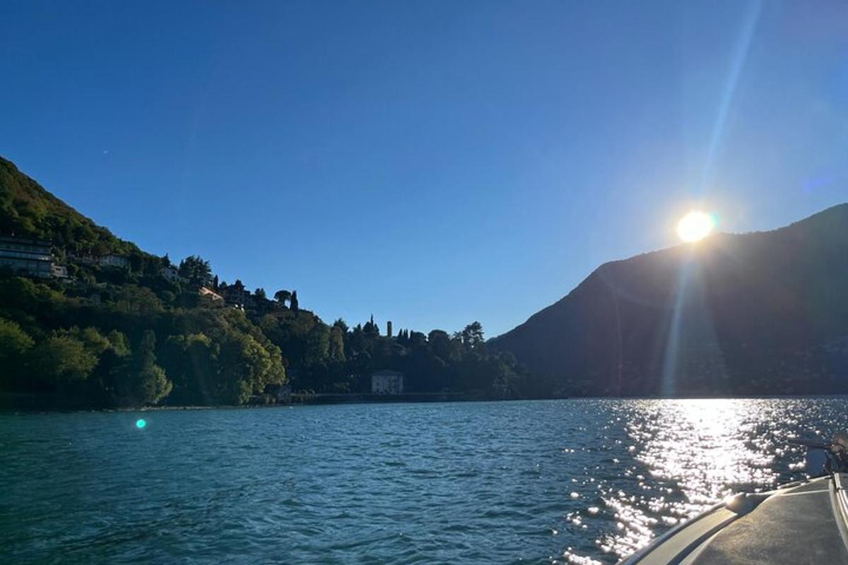 un vaixell en un llac amb el sol brillant sobre l'aigua