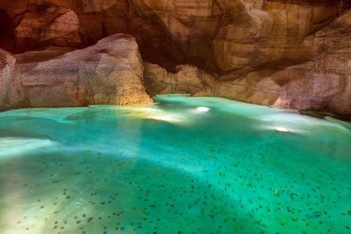 a pool of water in front of a rock wall