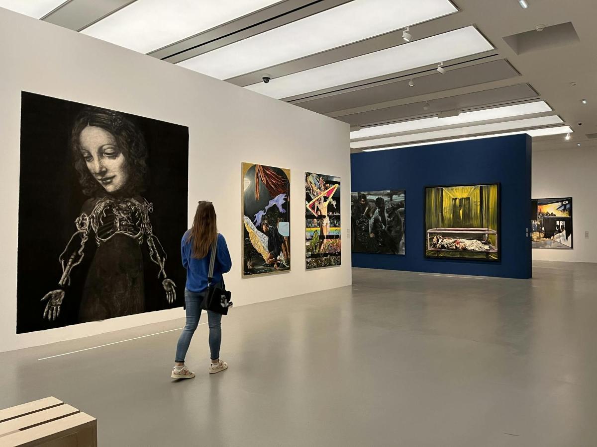 a woman standing in an art gallery looking at paintings