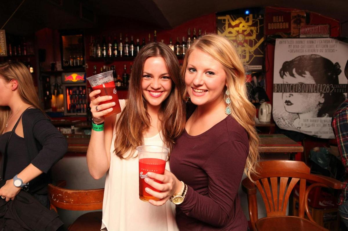 two women standing in a bar holding drinks