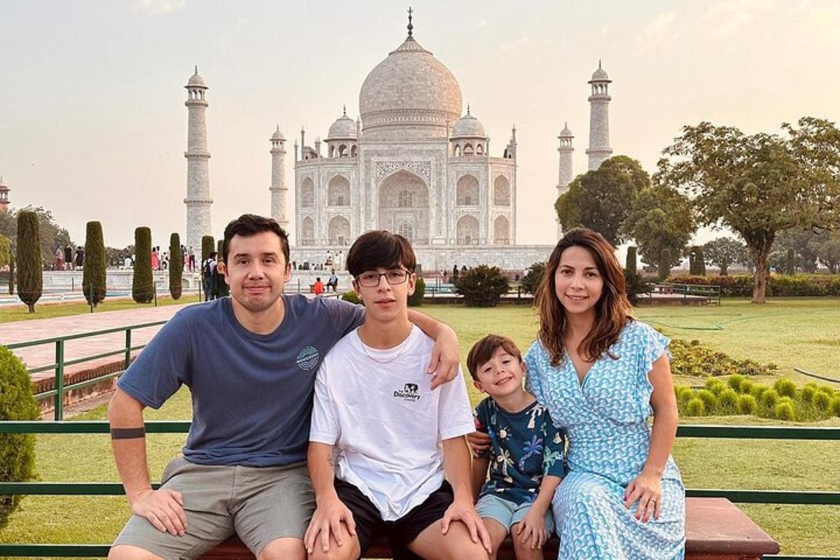 a family sitting on a bench in front of the taj mahal