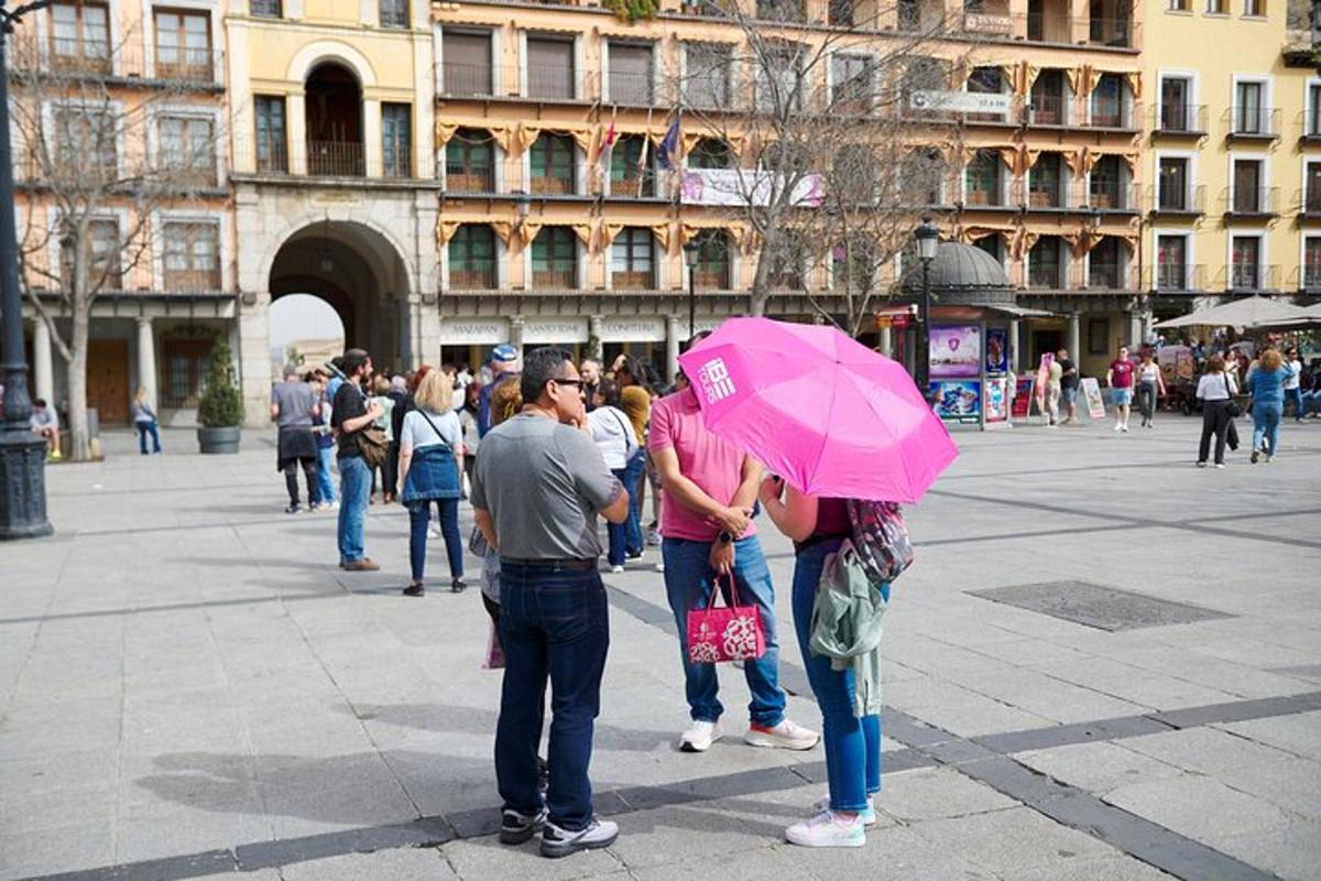 un gruppo di persone in piedi su una strada con un ombrello rosa