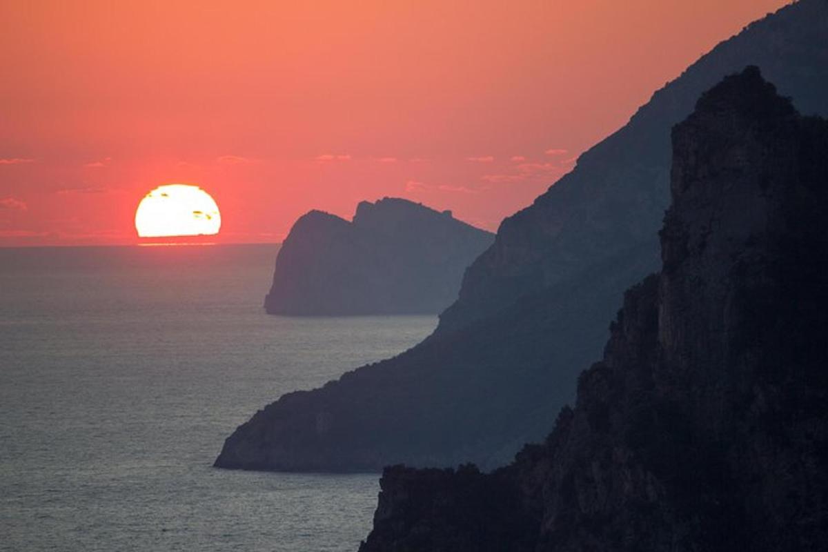un tramonto sull'oceano con una montagna