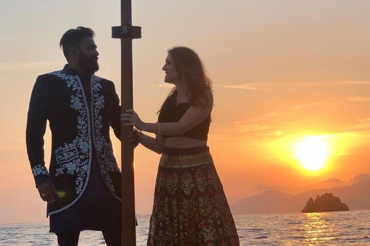 un uomo e una donna in piedi sulla spiaggia al tramonto