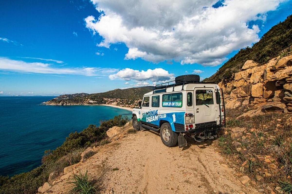 a vehicle parked on a dirt road next to the ocean