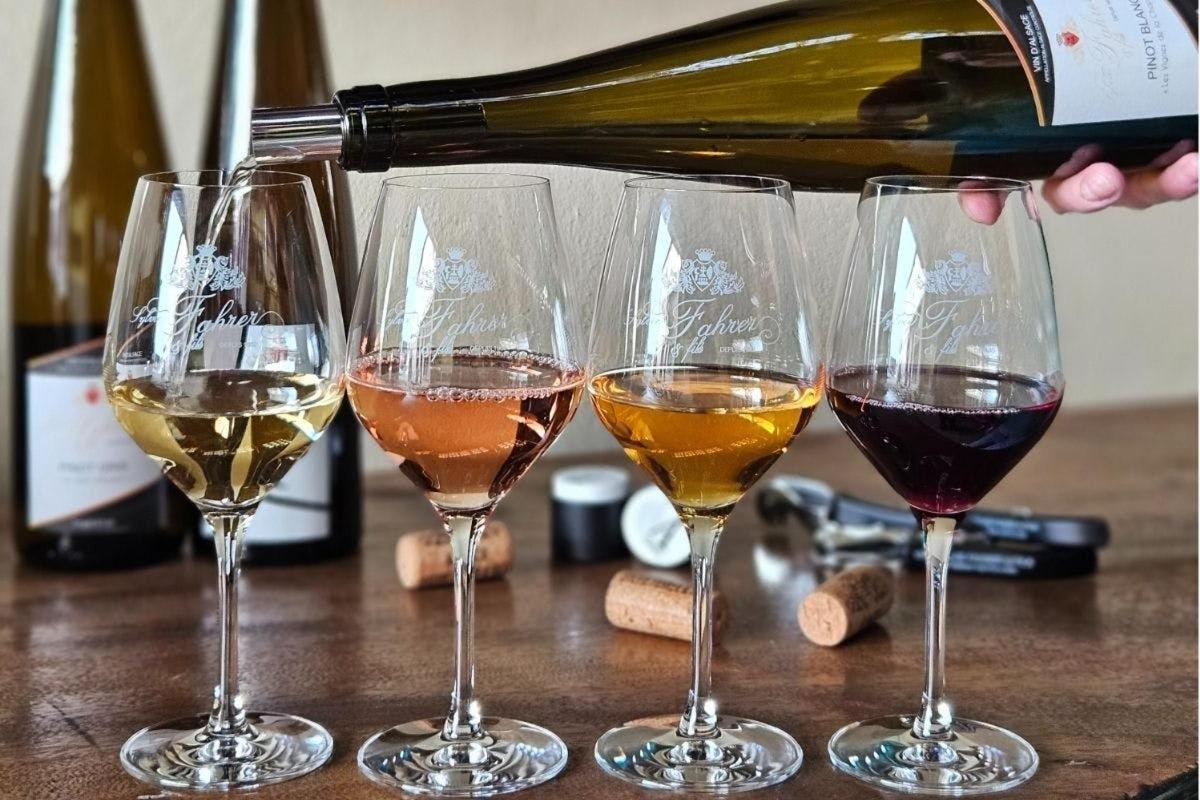 four wine glasses on a table with a bottle