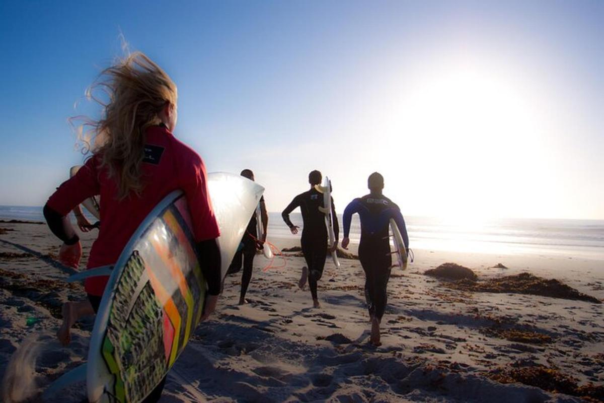 un gruppo di persone che camminano sulla spiaggia con le tavole da surf