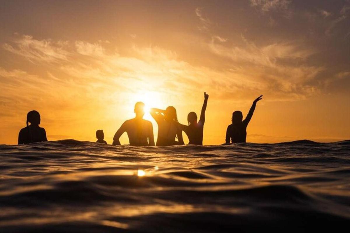 un gruppo di persone sedute nell'oceano al tramonto