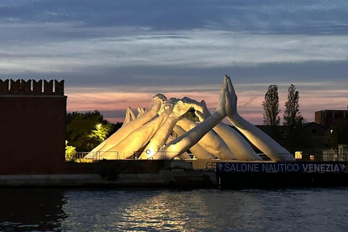 una grande scultura bianca seduta sul bordo di uno specchio d'acqua