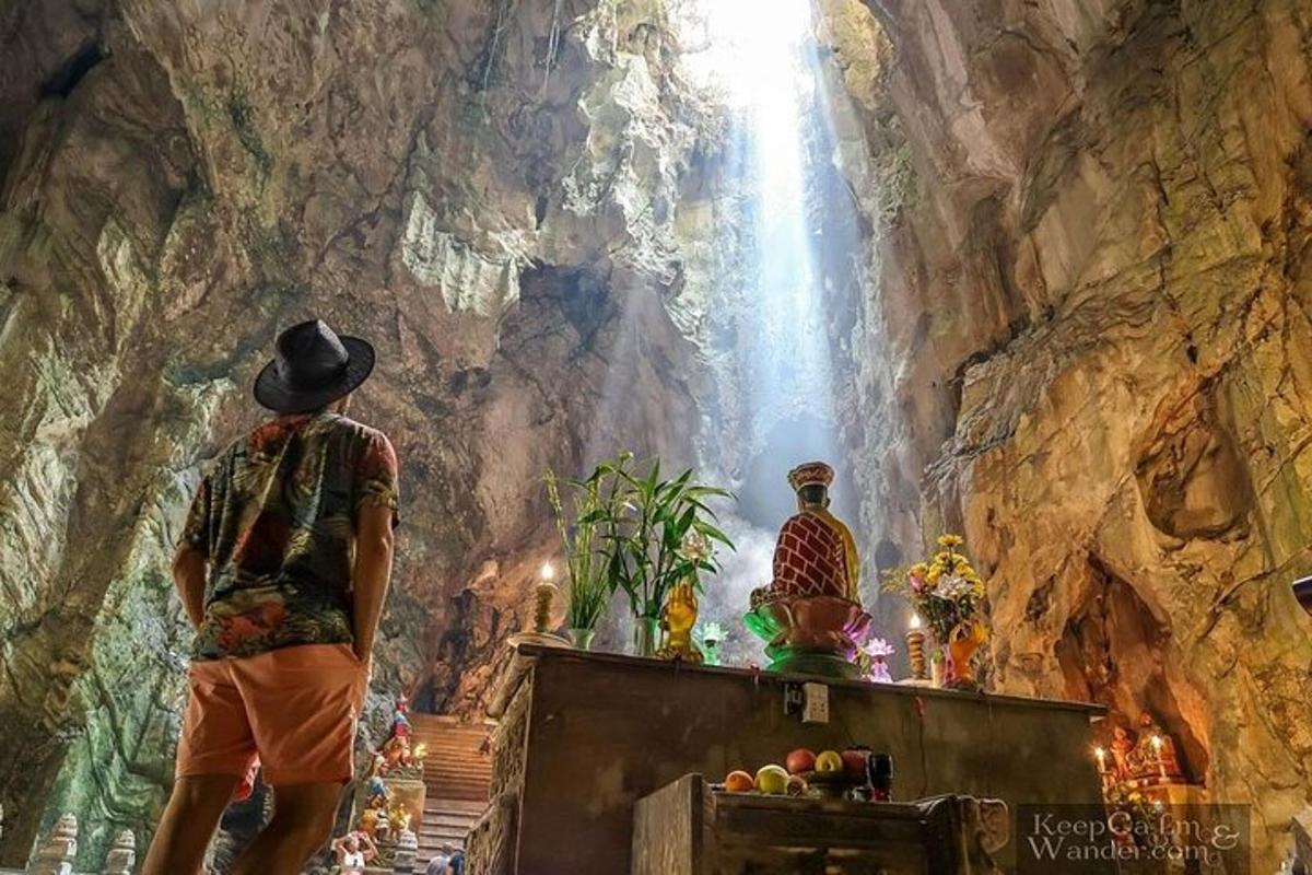seorang pria berdiri di dalam gua sambil melihat air terjun