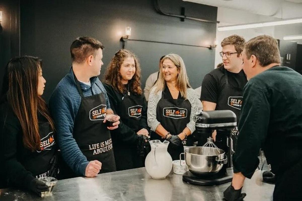 um grupo de pessoas em pé ao redor de um balcão em uma cozinha