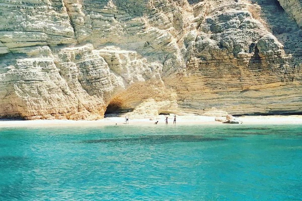 a group of people standing on a beach next to a cliff