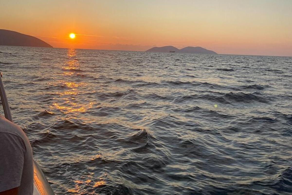 a boat in the ocean with the sun setting