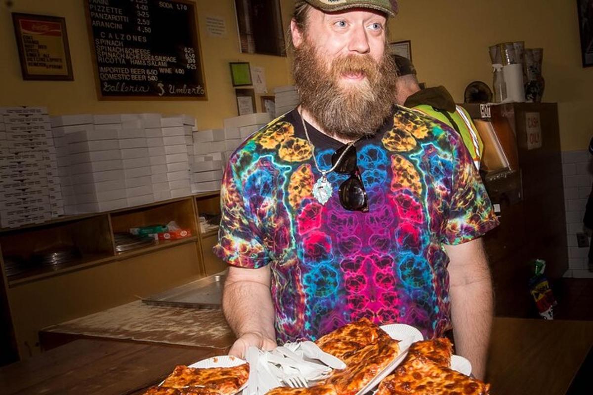 muž s vousy držící talíř pizzy