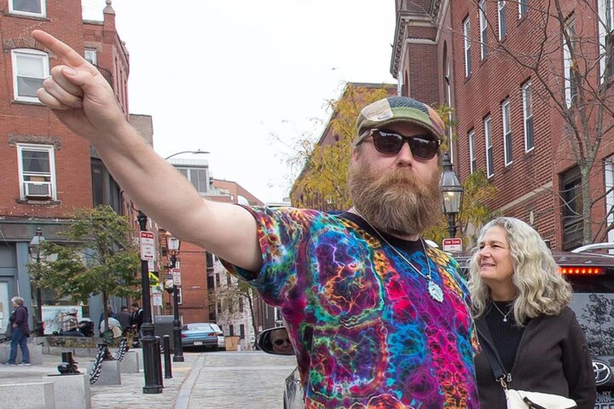 Un hombre con una camisa colorida de pie en una calle de la ciudad.