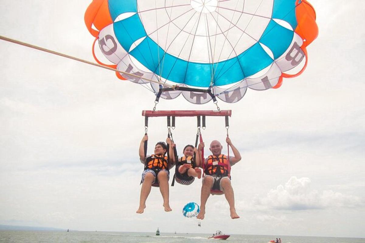 two people are hanging from a parachute on the beach