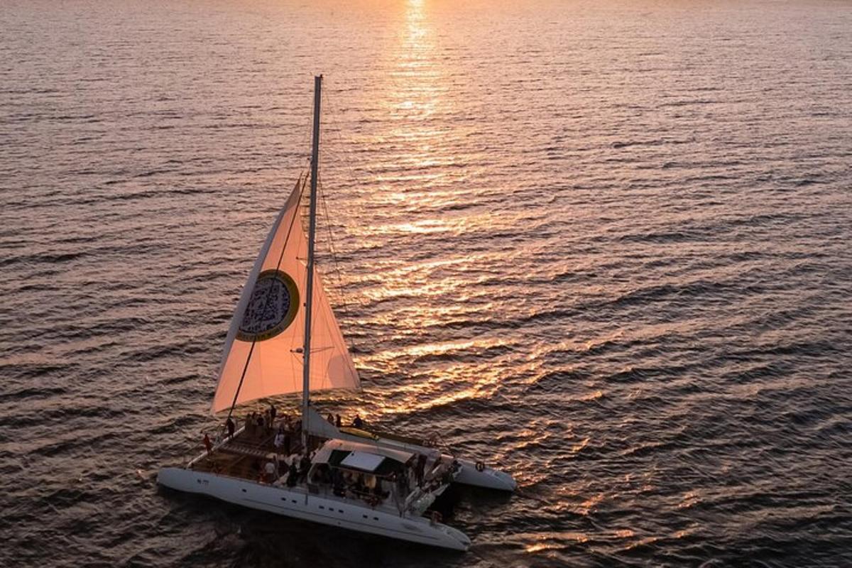 a small sail boat in the water at sunset