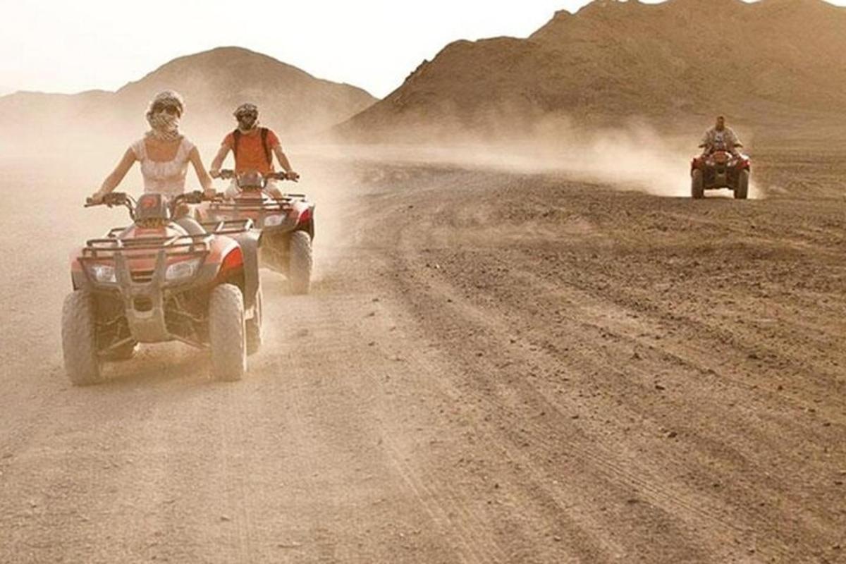 duas pessoas andando de quadriciclo em uma estrada de terra