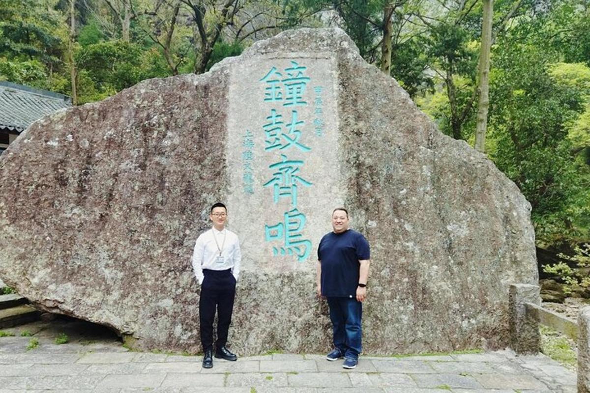 two men standing in front of a large rock