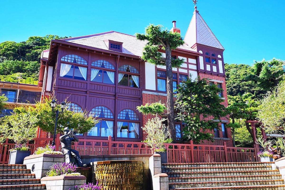 una grande casa rossa con una statua di fronte