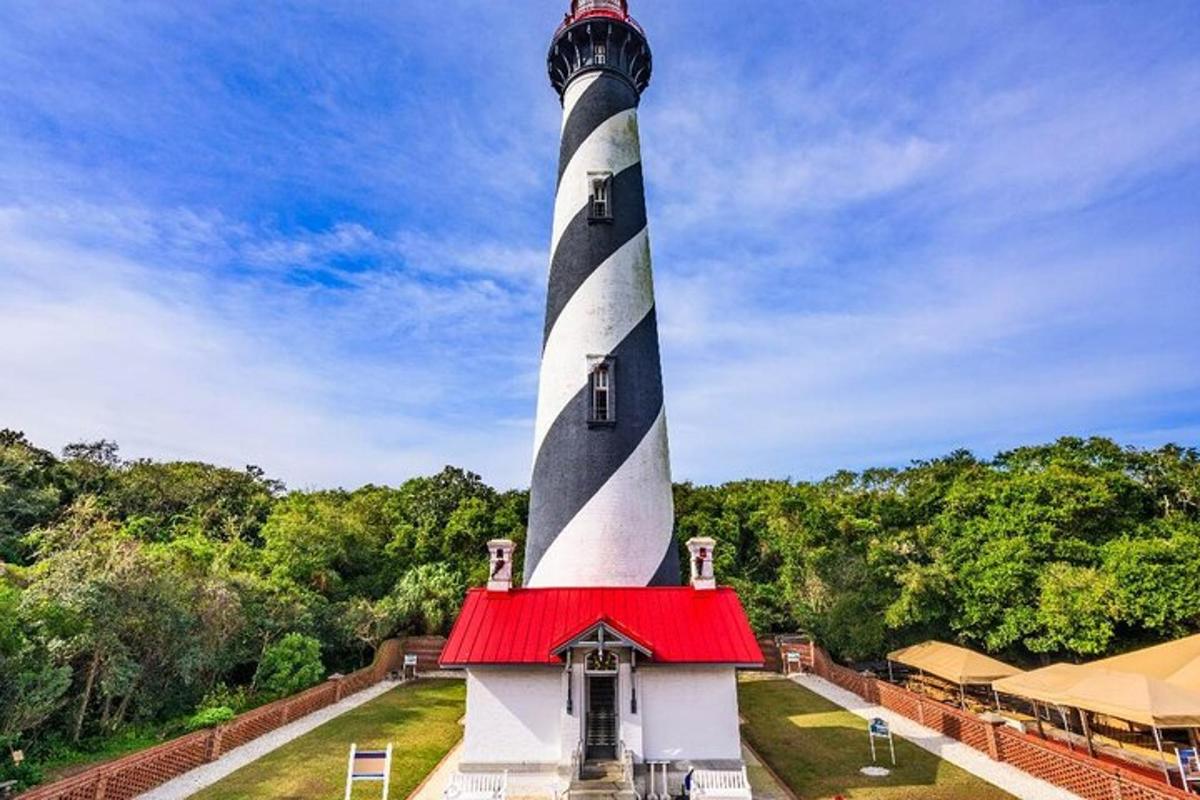 a black and white lighthouse with a red roof