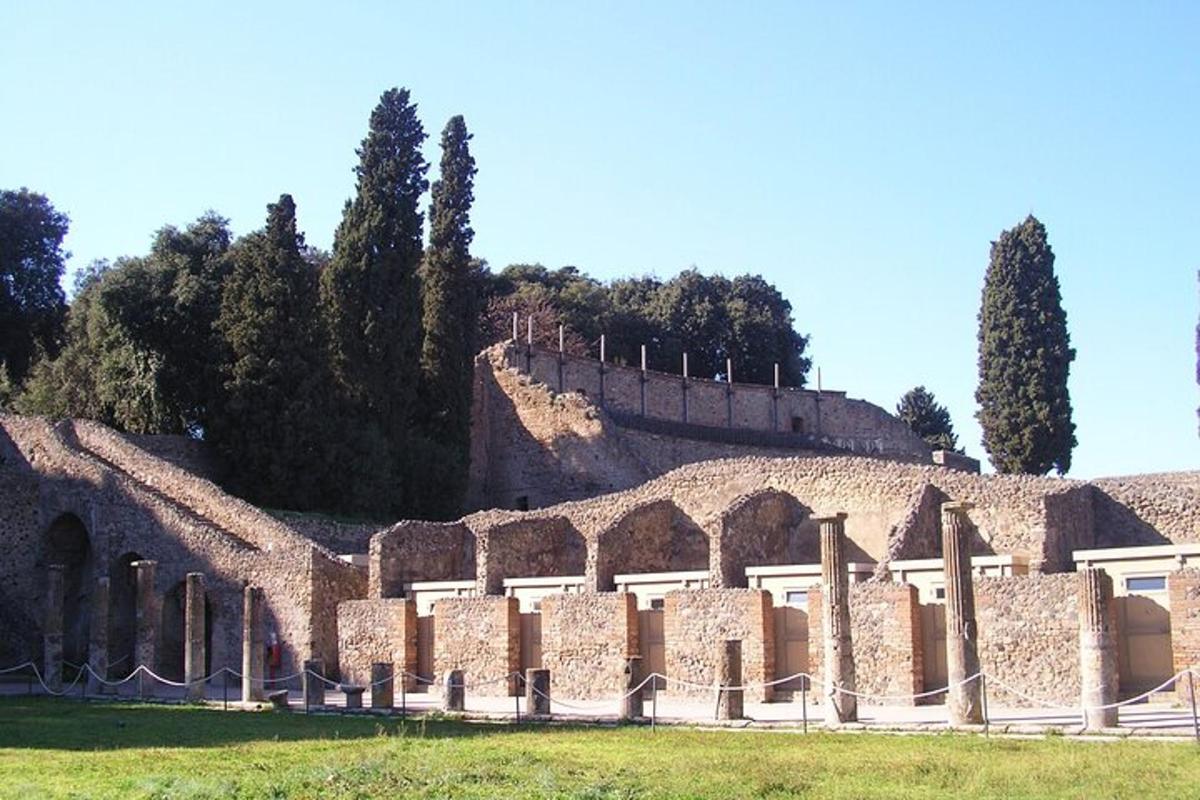 Un edificio de piedra con árboles y una colina.