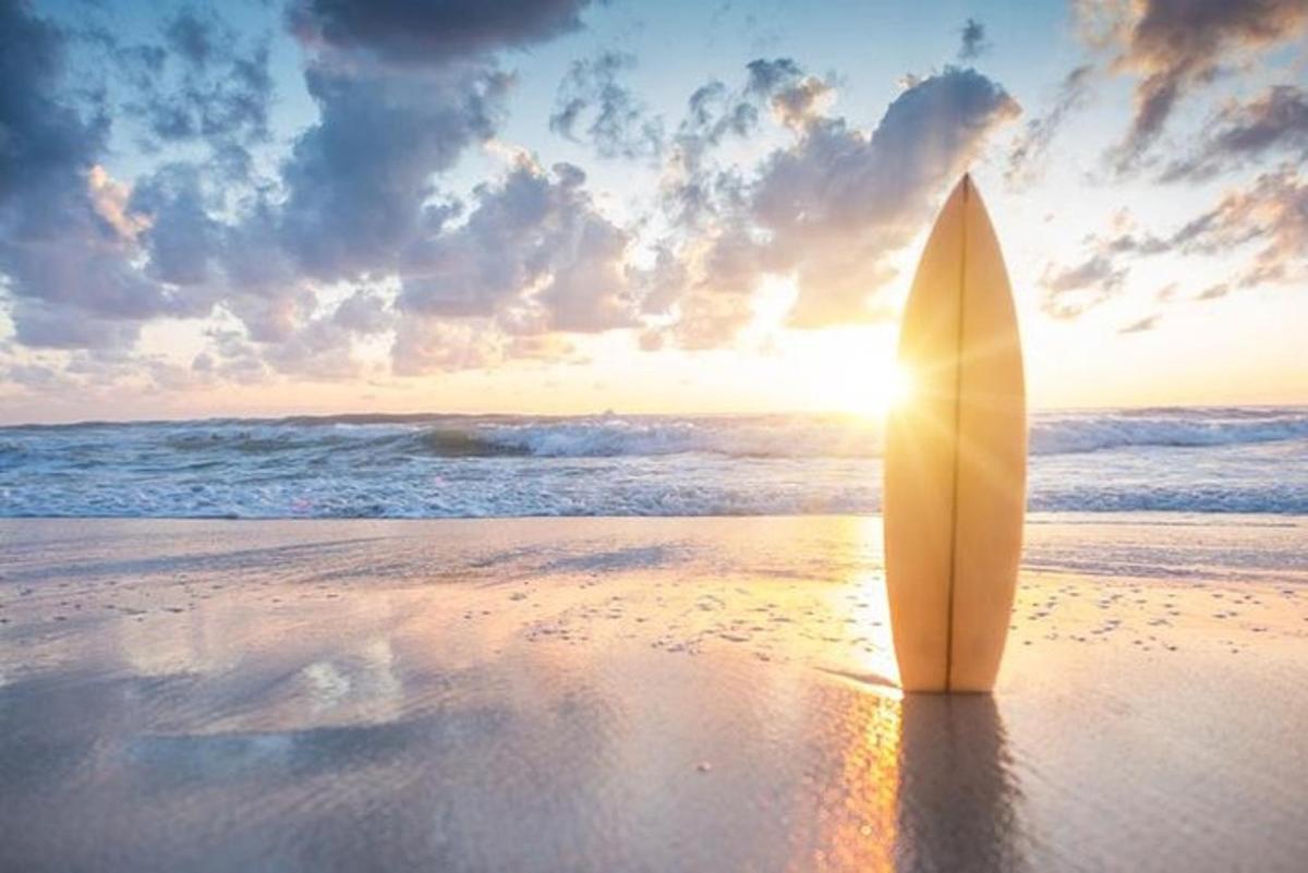 papan selancar yang terletak di pantai saat matahari terbenam