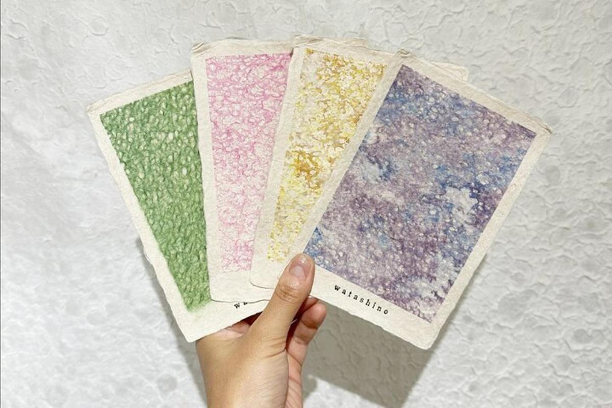 una mano che tiene in mano quattro fogli di carta di colore diverso