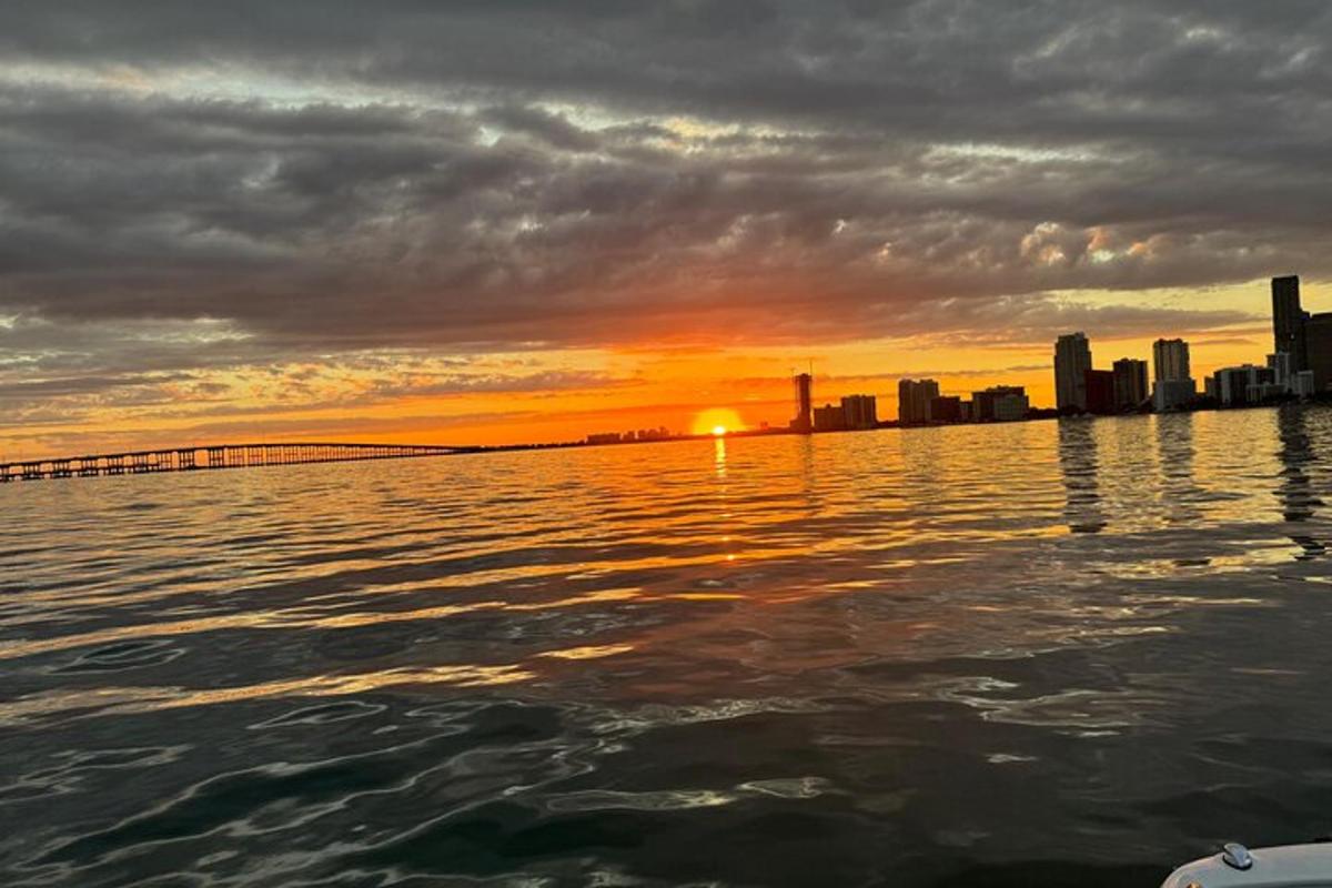 un tramonto sull'acqua con una città sullo sfondo