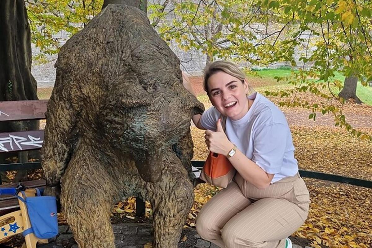 a woman kneeling next to a statue of a bear