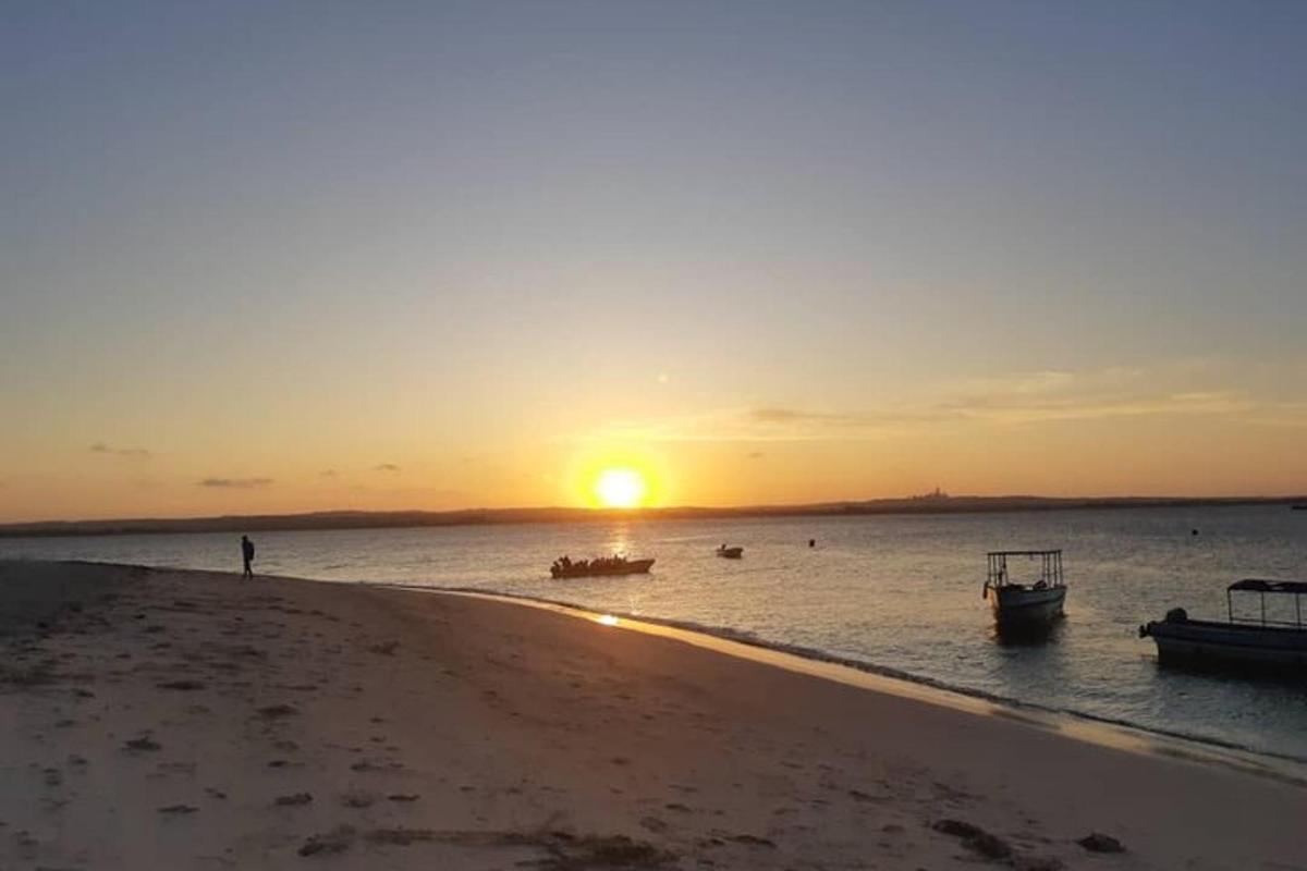 sončni zahod na plaži s čolni v vodi