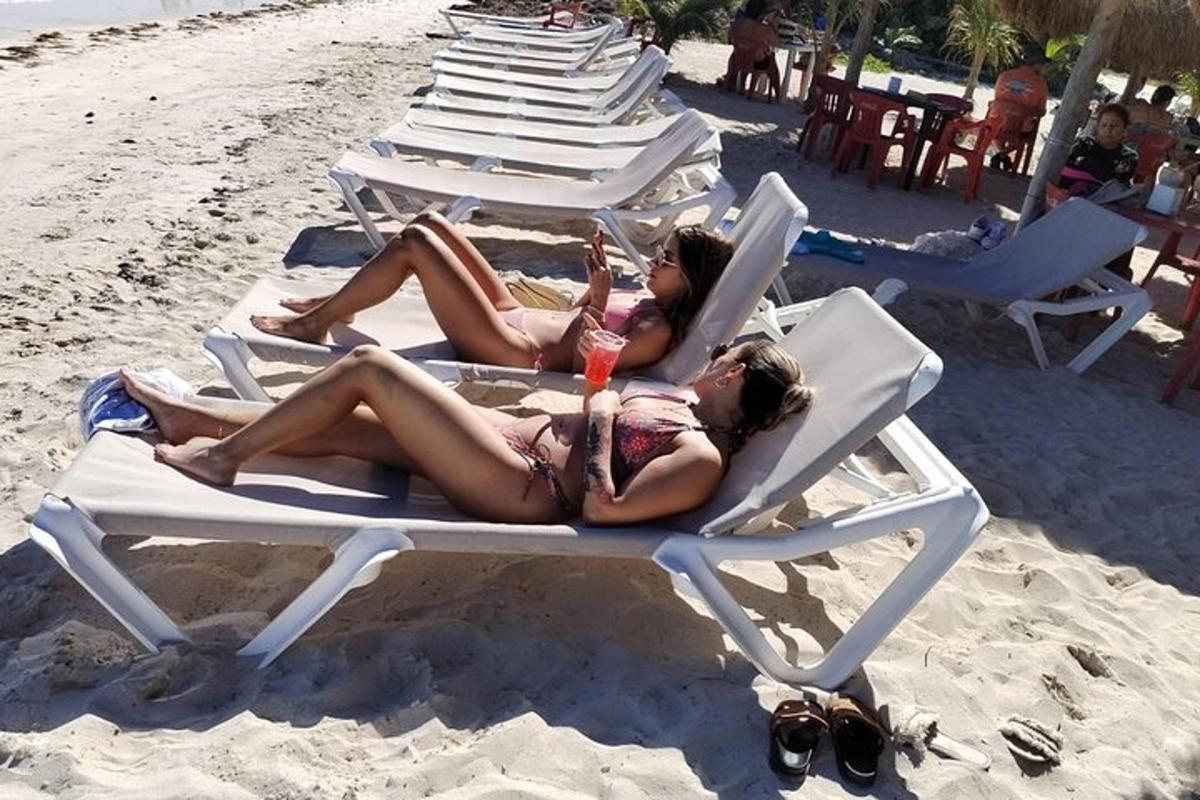 two women laying in lawn chairs on the beach