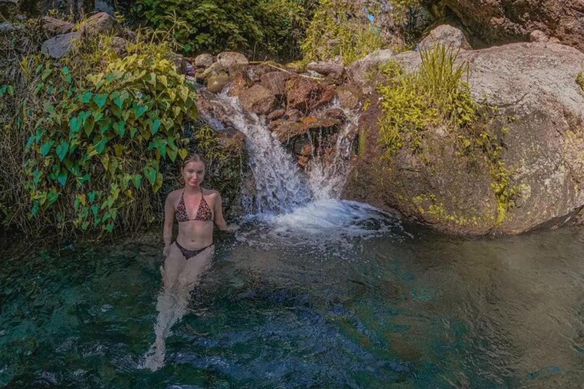 una donna in piedi nell'acqua di fronte a una cascata