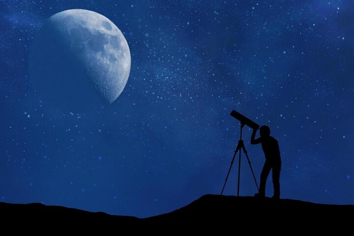a man looking at the moon through a telescope