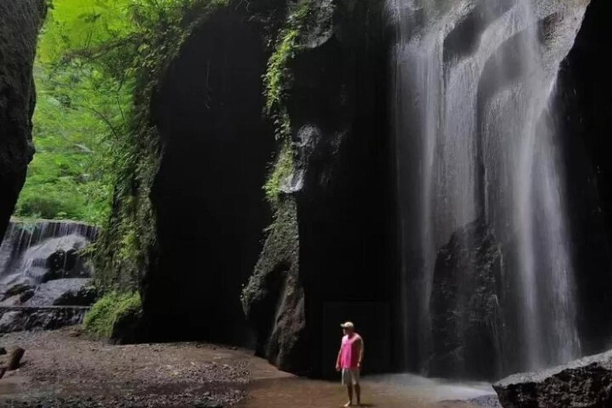uma pessoa parada em frente a uma cachoeira