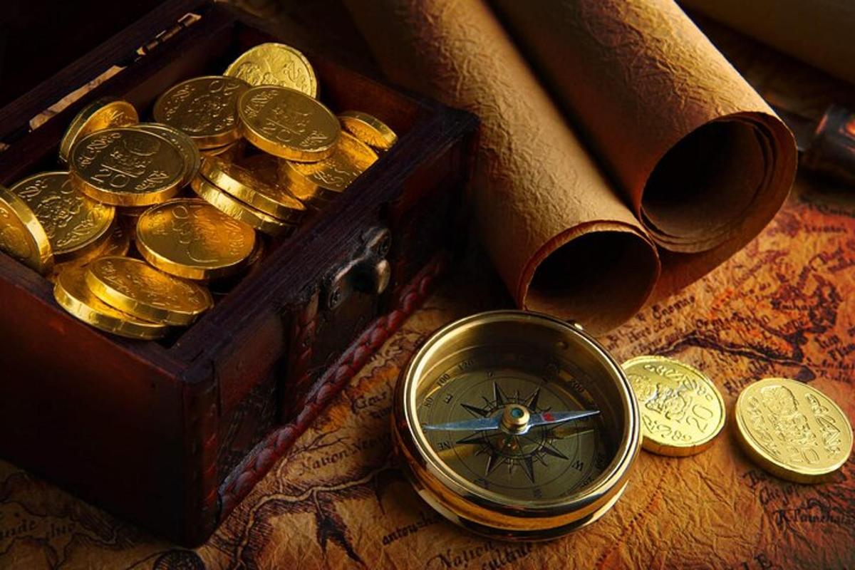 uma pilha de moedas de ouro ao lado de uma caixa de madeira