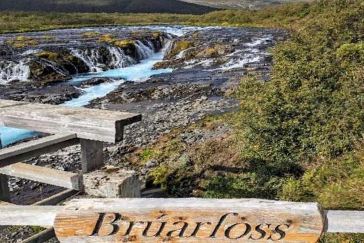 a wooden bench next to a river with a waterfall