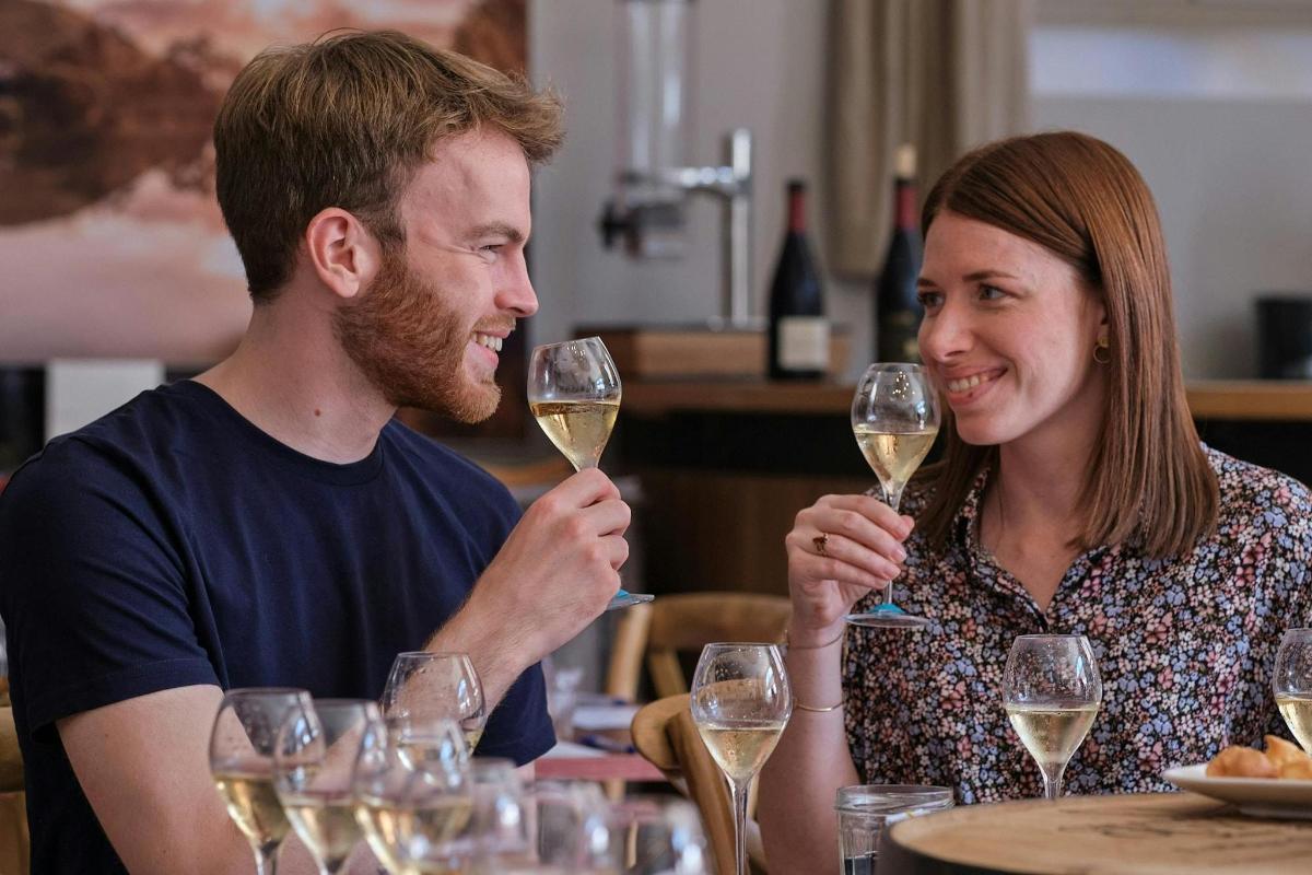 a man and woman sitting at a table with wine glasses