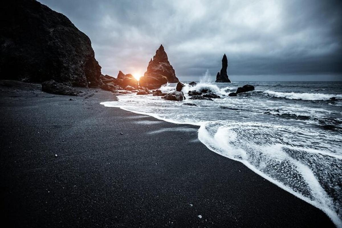 a beach with rocks in the ocean with the sunset