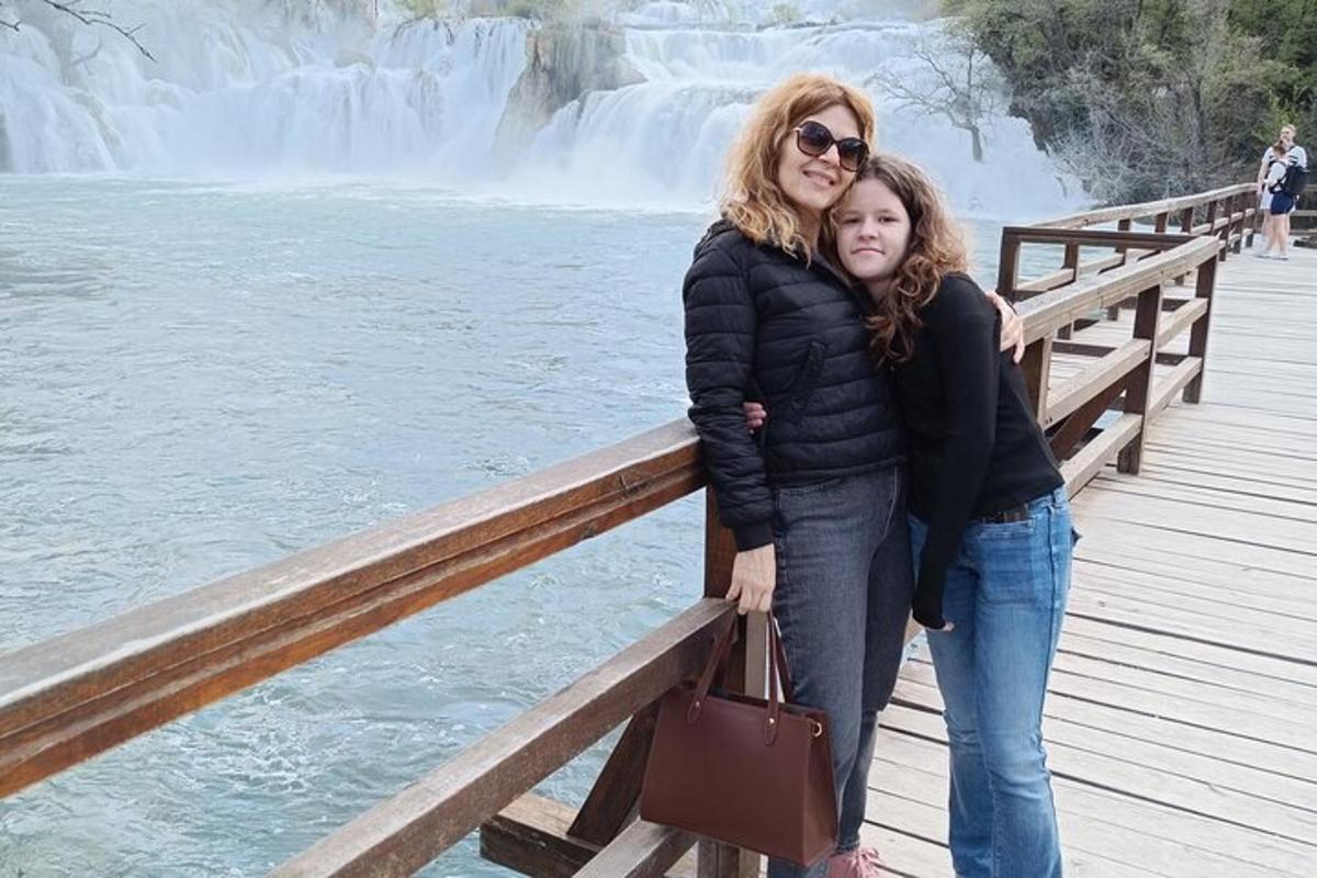 seorang wanita dan seorang gadis berdiri di atas jeti berhampiran air