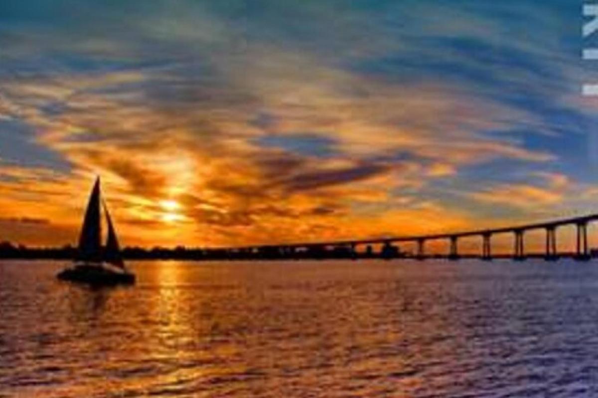 a sail boat in the water near a bridge