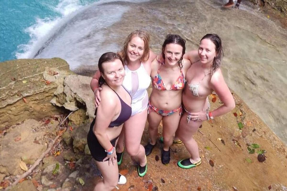 Čtyři ženy v bikinách stojící na skále u vody