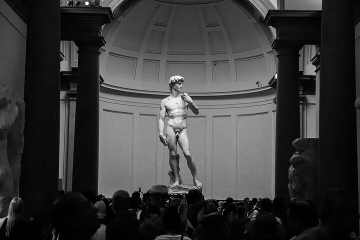 uma estátua de um homem em pé em um palco em frente a uma multidão