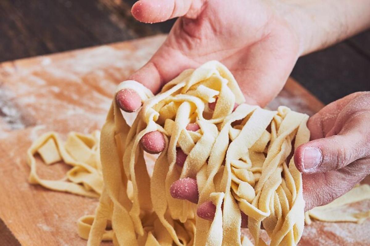a person holding a bunch of pasta on a cutting board