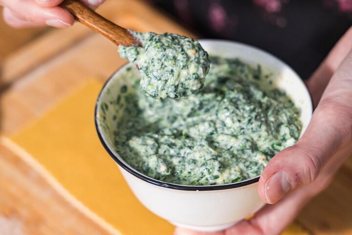 a person holding a bowl of pesto with a wooden spoon