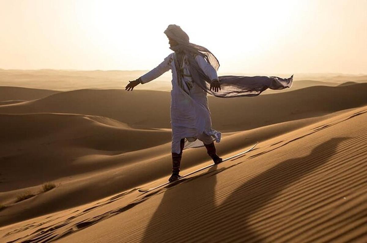 a man walking on a sand dune in the desert