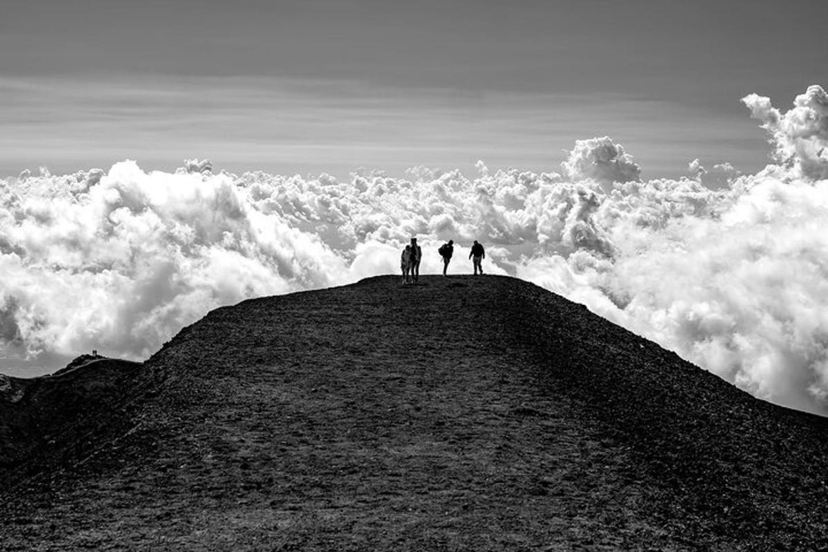 due persone in piedi sulla cima di una collina che domina le nuvole