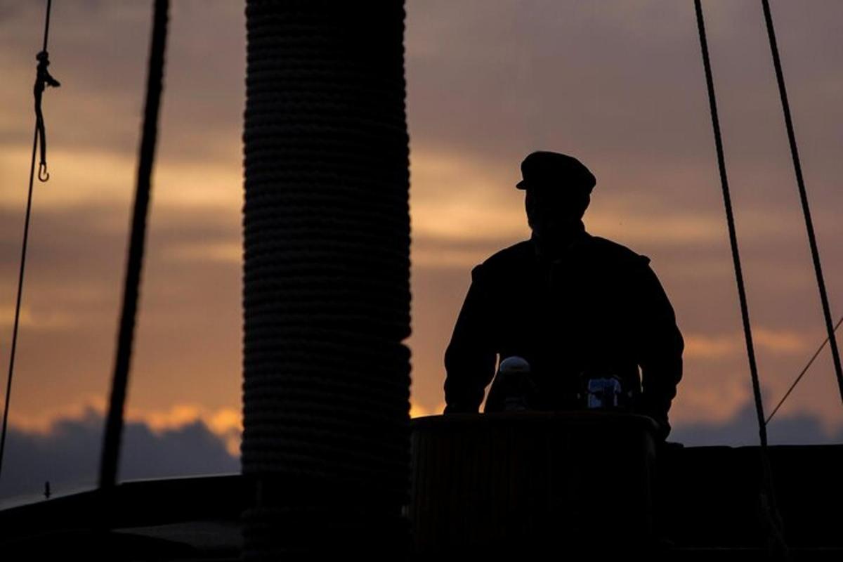 a silhouette of a man standing next to a pole